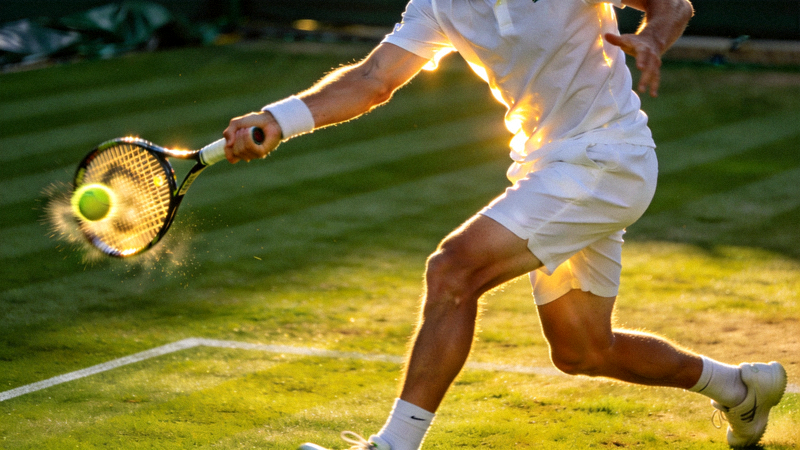 温布尔登网球锦标赛草地赛场，运动员正手大力击球瞬间